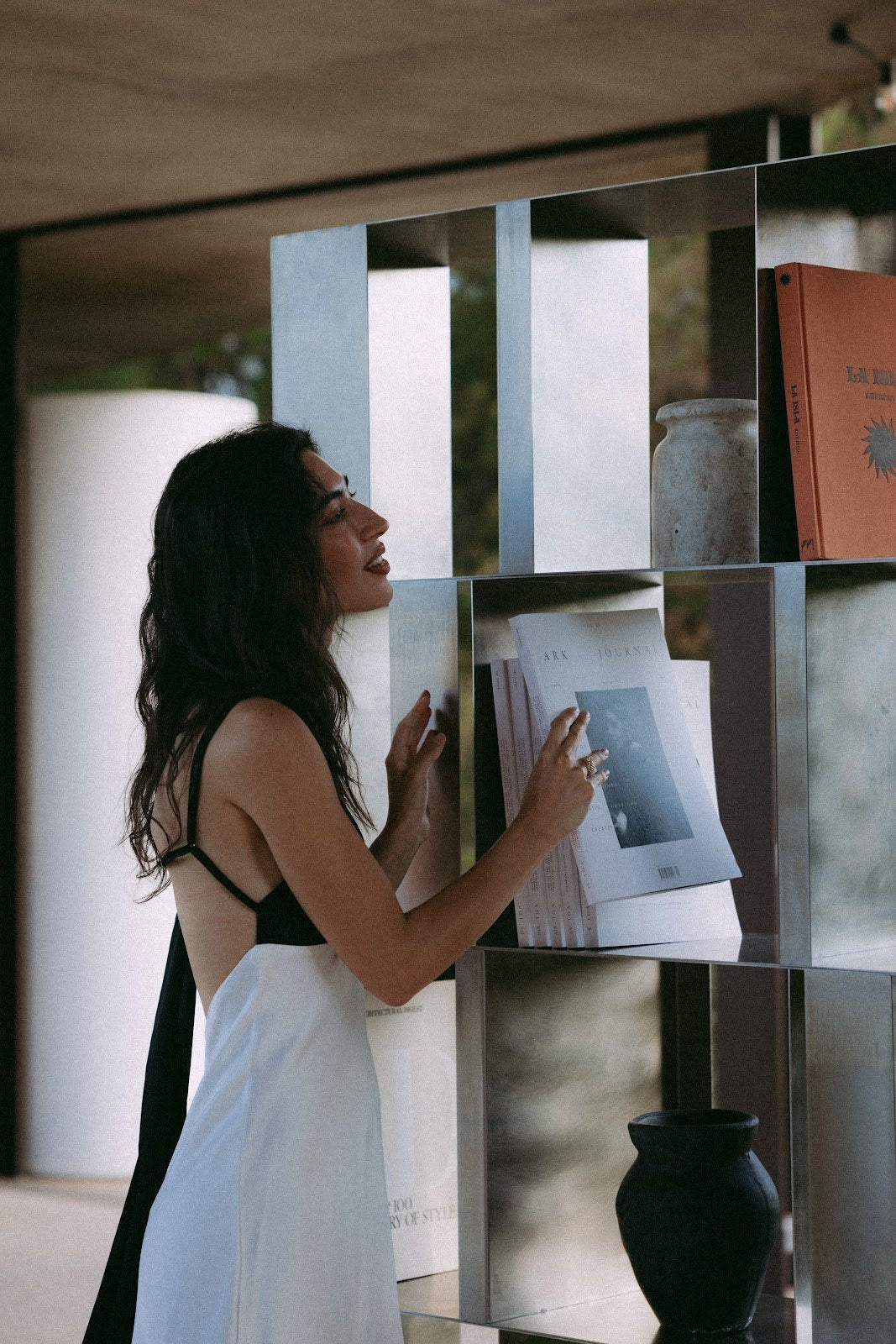 Mujer colocando un libro en la INFINITY BOOKSHELF de acero inoxidable