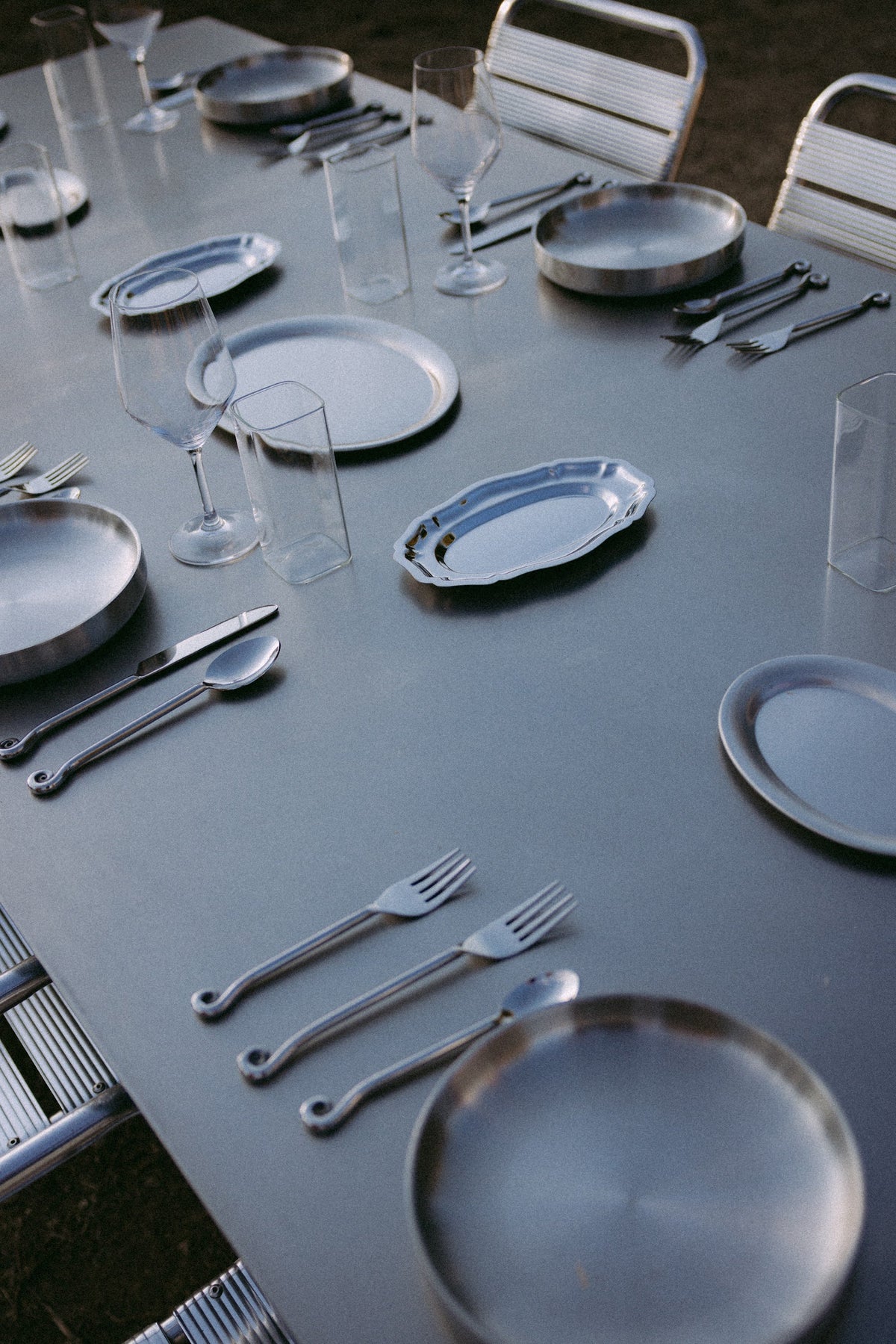 ZEN DINING TABLE de acero inoxidable puesta con platos y copas
