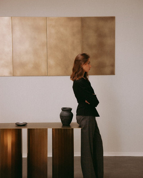 Lookbook : femme devant un mur en laiton avec la TUKKON CONSOLE