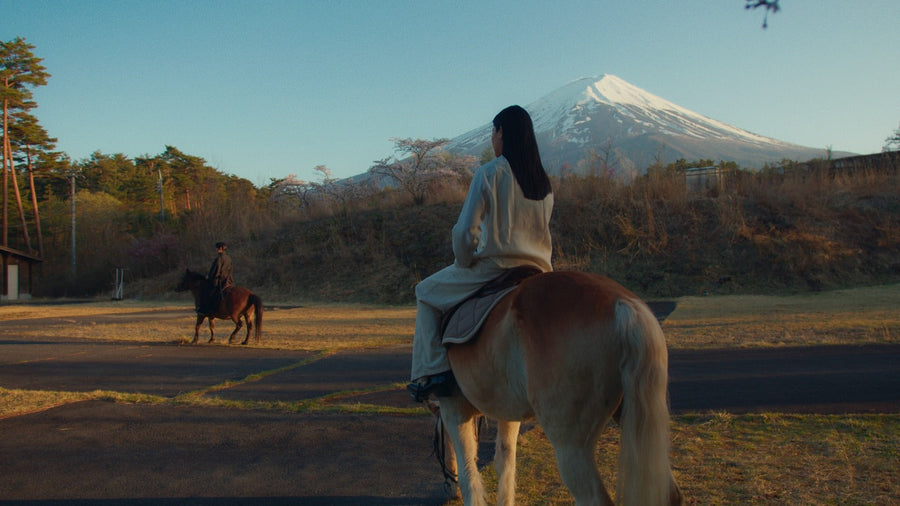 Geisha auf einem Pferd vor dem Mount Fuji, dahinter ein zweiter Reiter