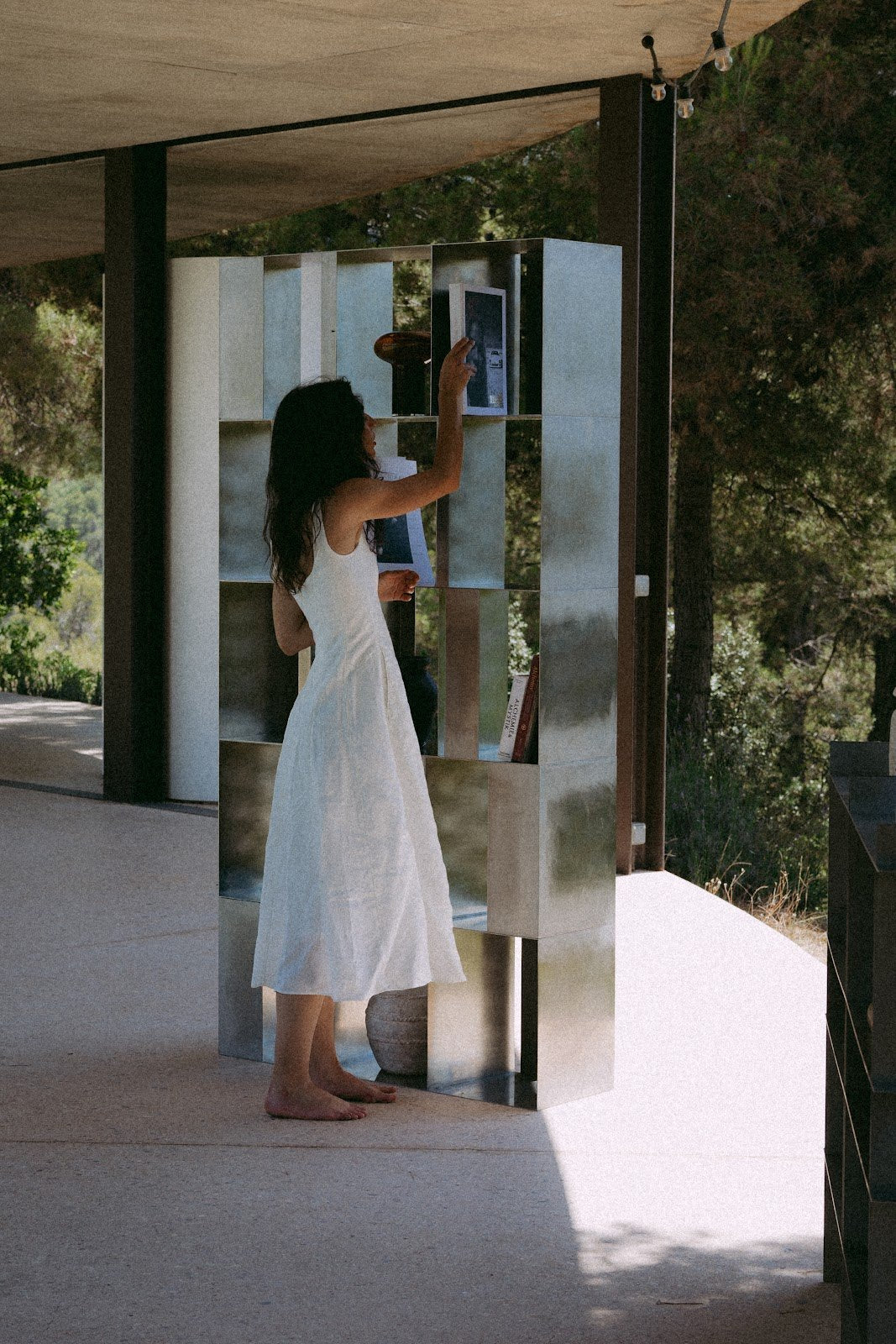 Donna accanto all’INFINITY BOOKSHELF in acciaio inox sulla terrazza della Solo House