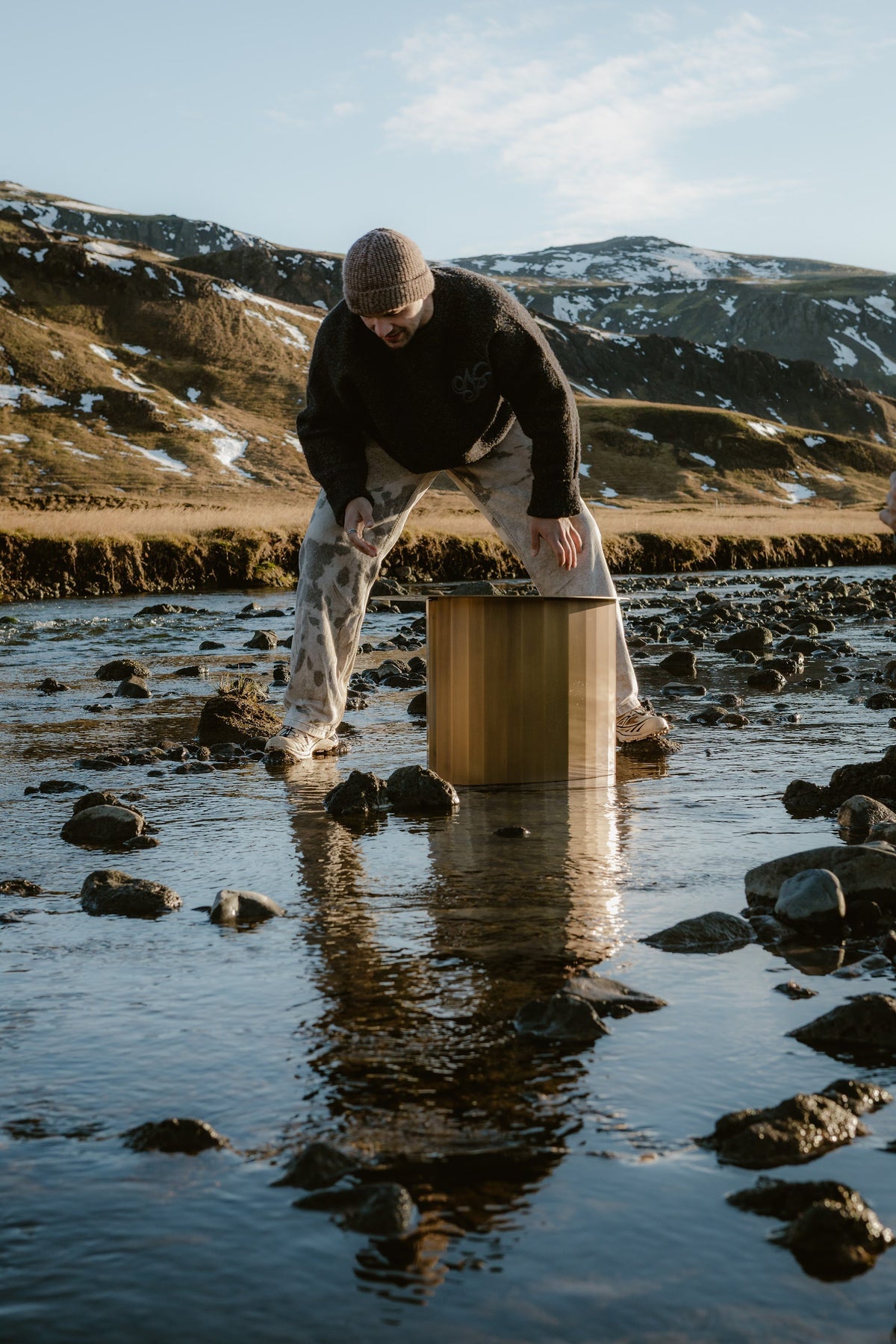 Der TUKKON SIDE TABLE aus Messing wird in einen Fluss in Island gestellt