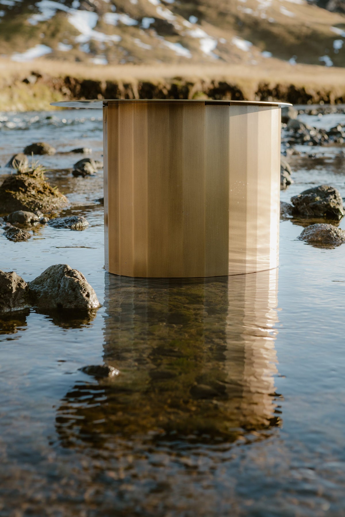 TUKKON SIDE TABLE aus Messing im Fluss, Wasser spiegelt sich im Metall